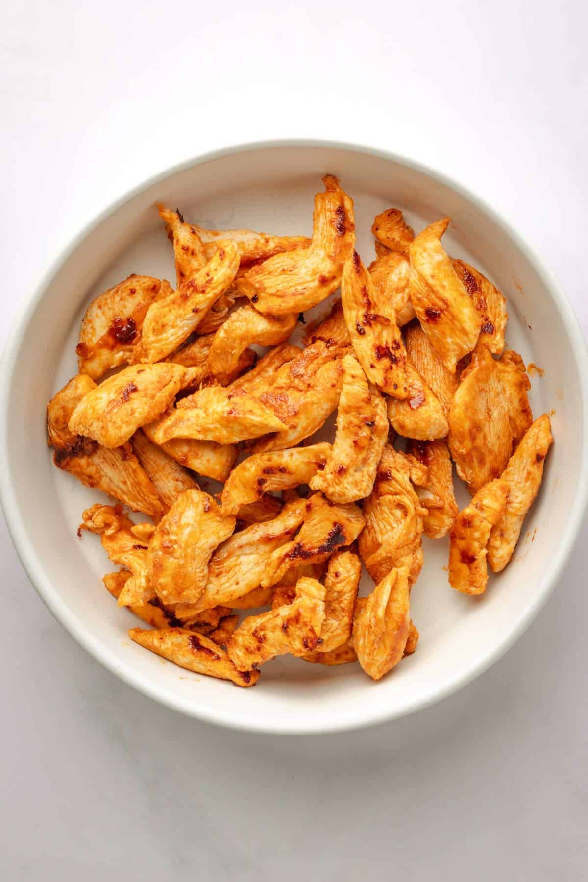 Chicken strips in a bowl with buffalo sauce.