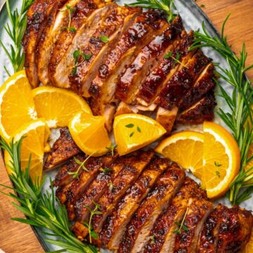 two sliced turkey breasts with oranges and rosemary.