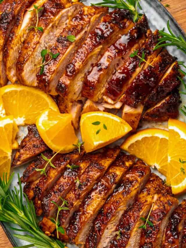 two sliced turkey breasts with oranges and rosemary.