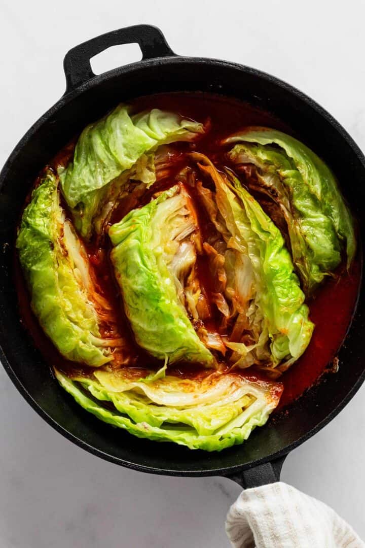 cabbage wedges in tomato sauce in skillet.