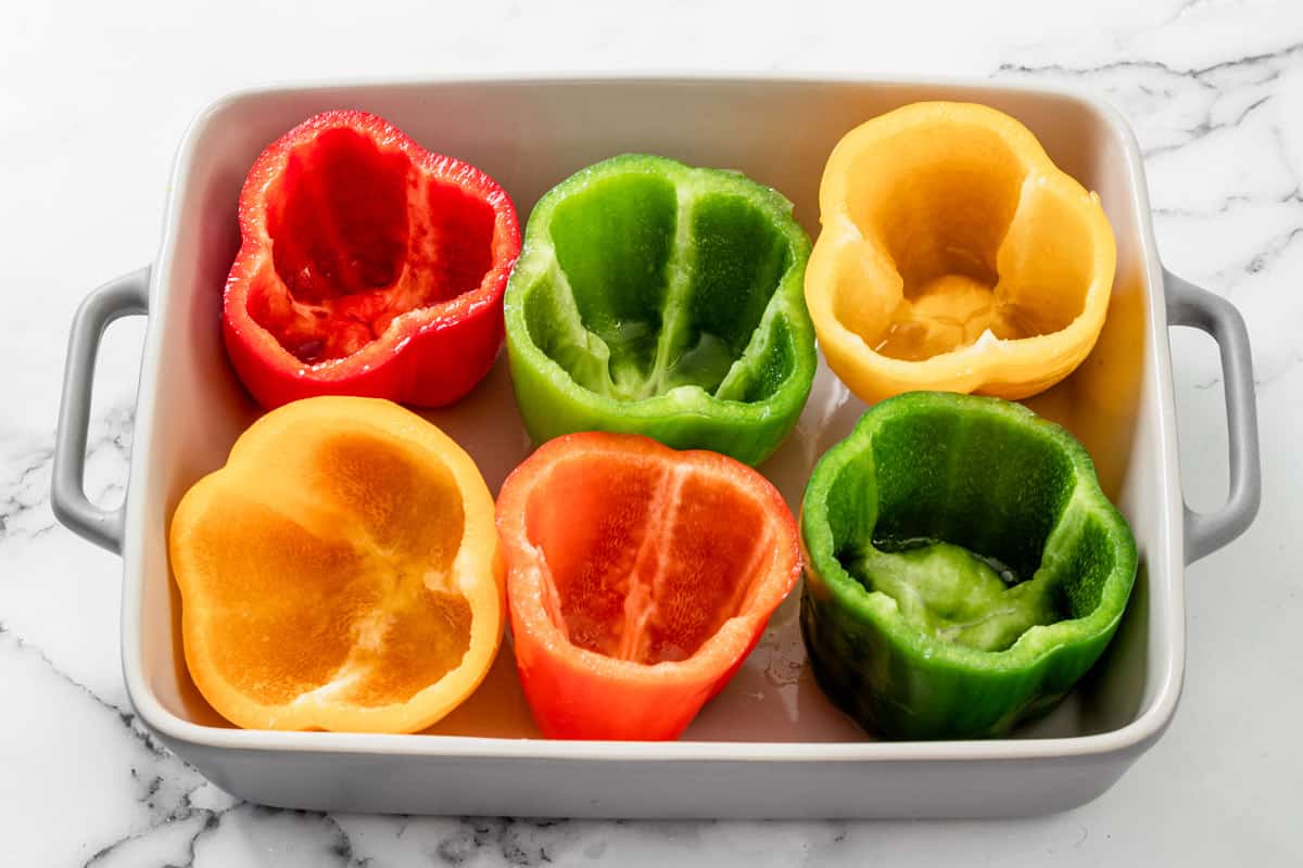 six empty bell peppers in baking dish