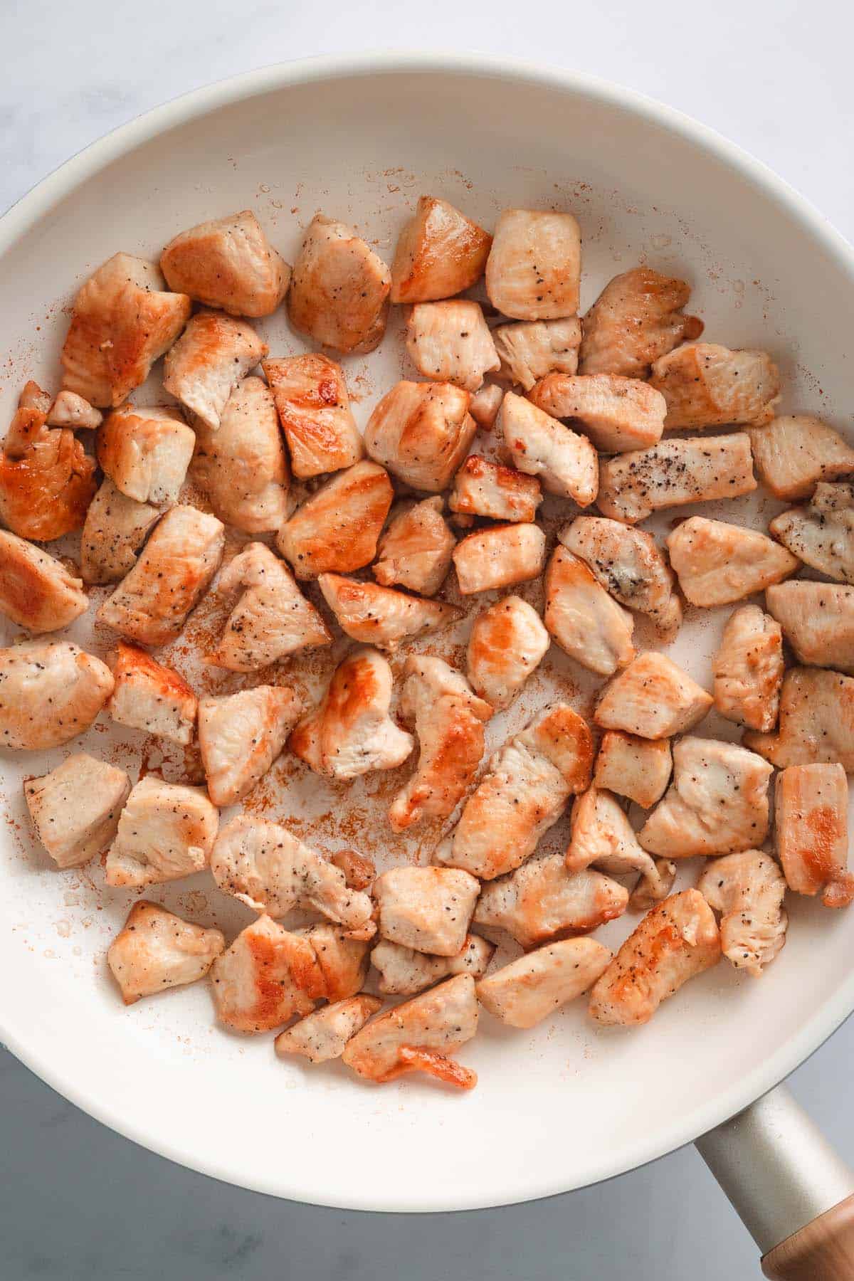 Diced seasoned chicken pieces spread on a baking sheet.