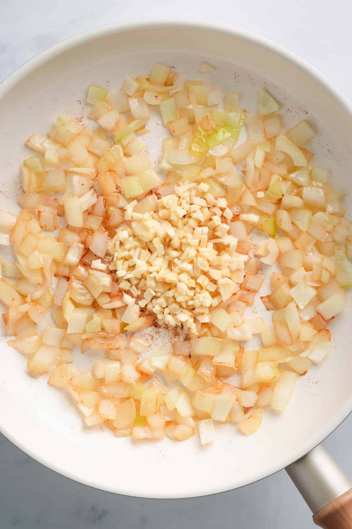 Chopped onion and minced garlic on a white plate.
