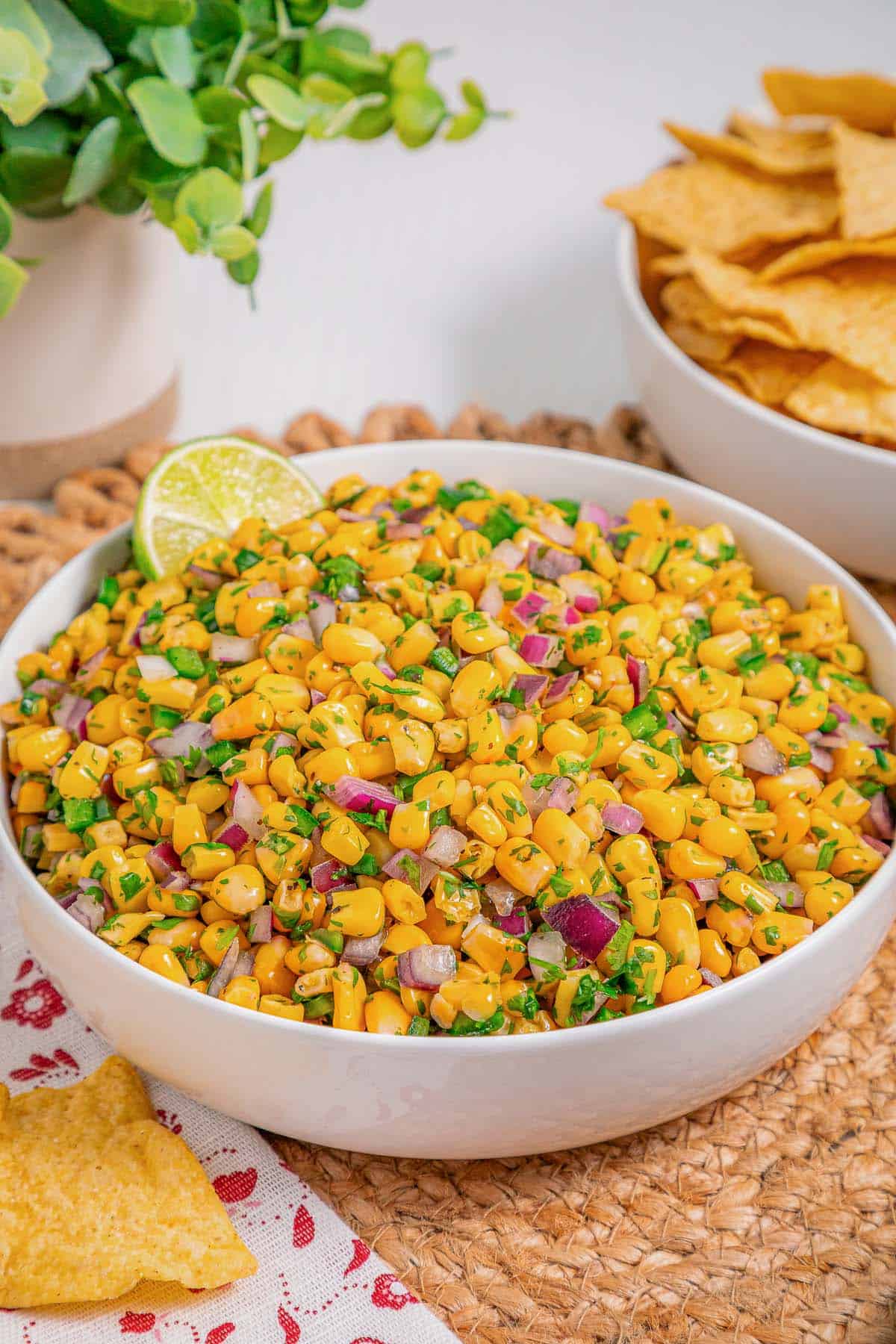 Fresh chipotle corn salsa served in a white bowl with tortilla chips on the side.