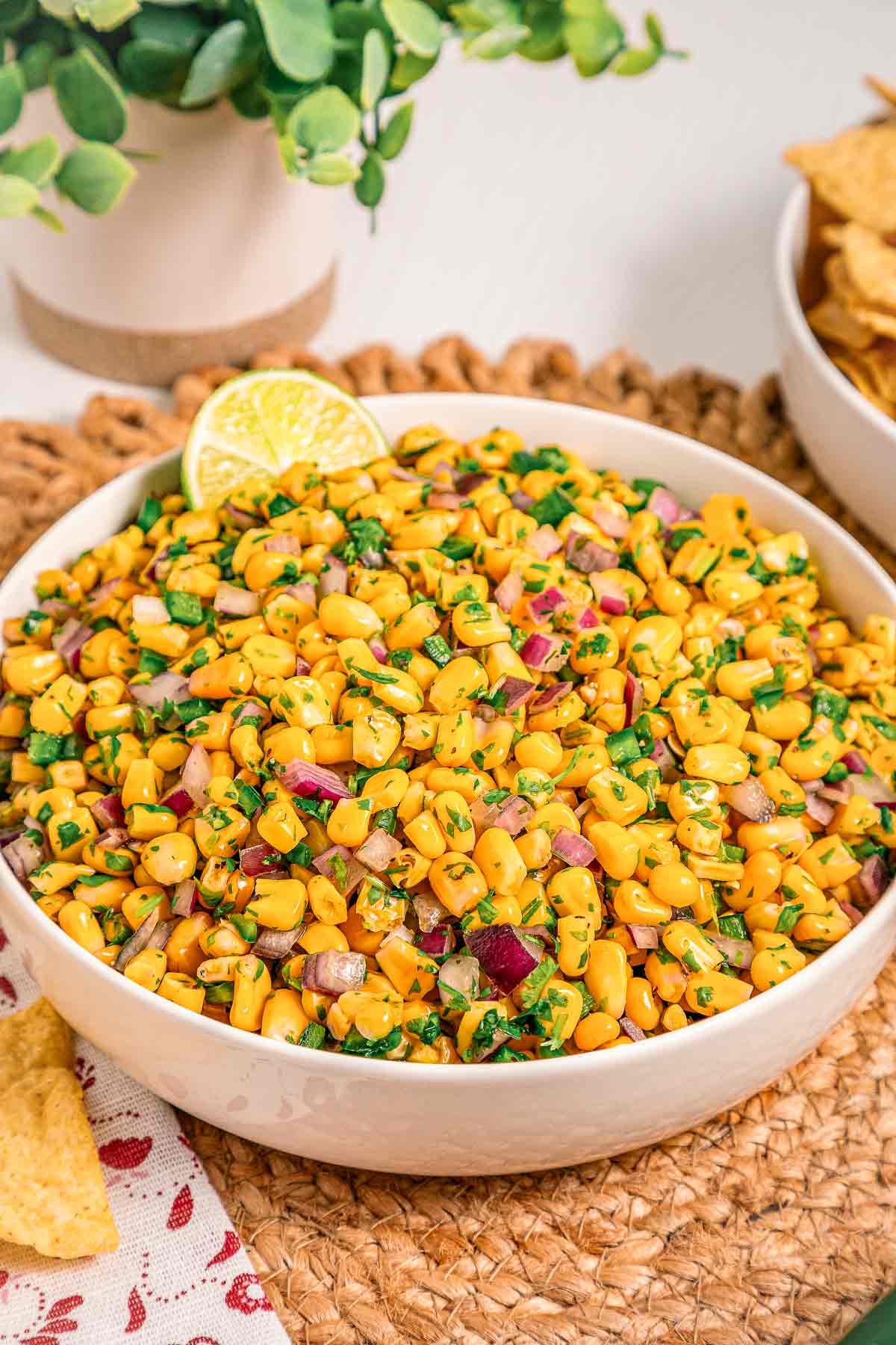 Fresh chipotle corn salsa served in a white bowl with tortilla chips on the side.