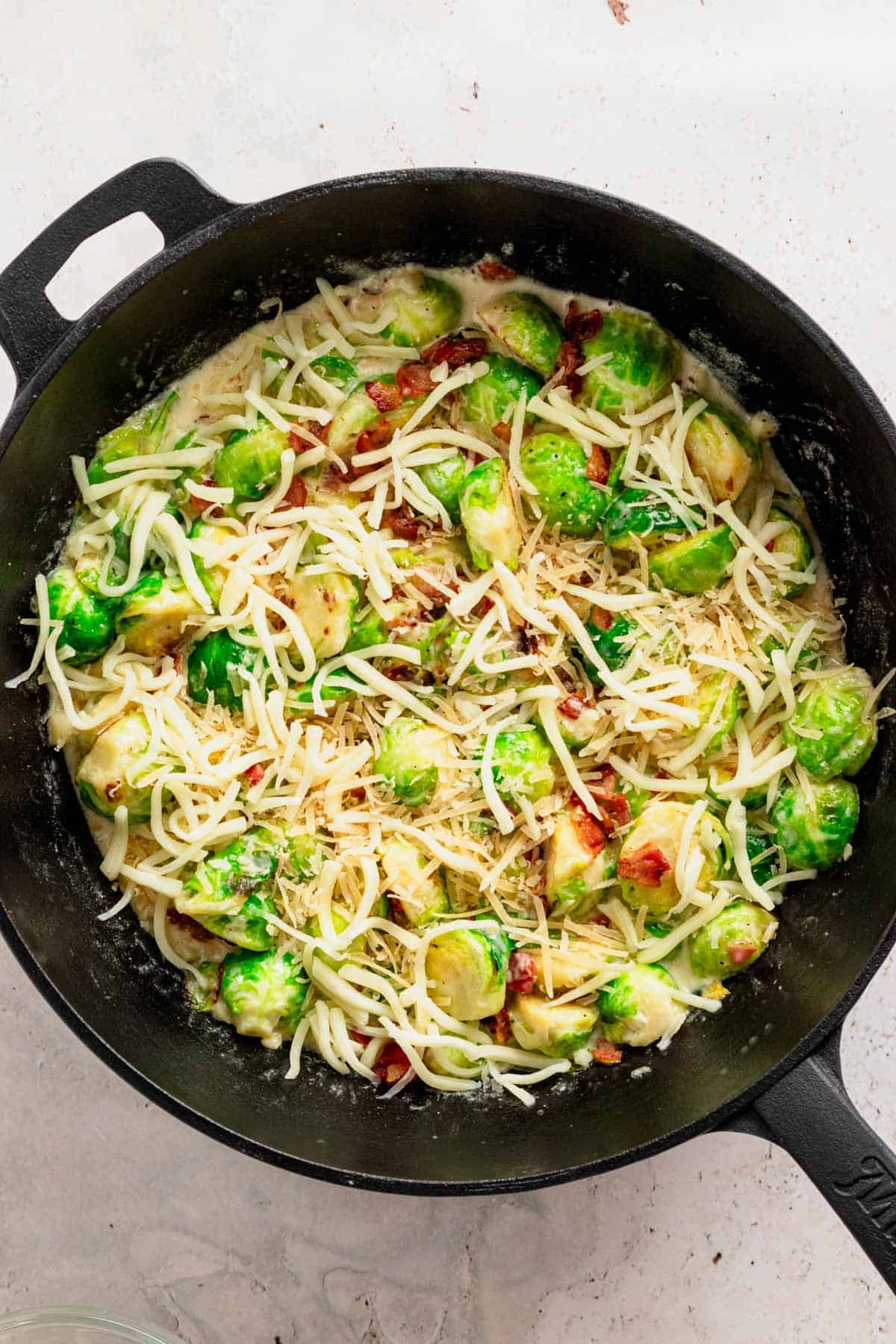 adding grated cheese on top of brussel sprouts.