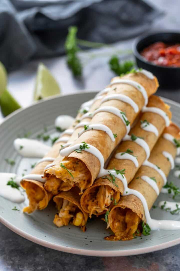 Creamy Chicken Taquitos stacked on top of each other and drizzled with sriracha mayonnaise