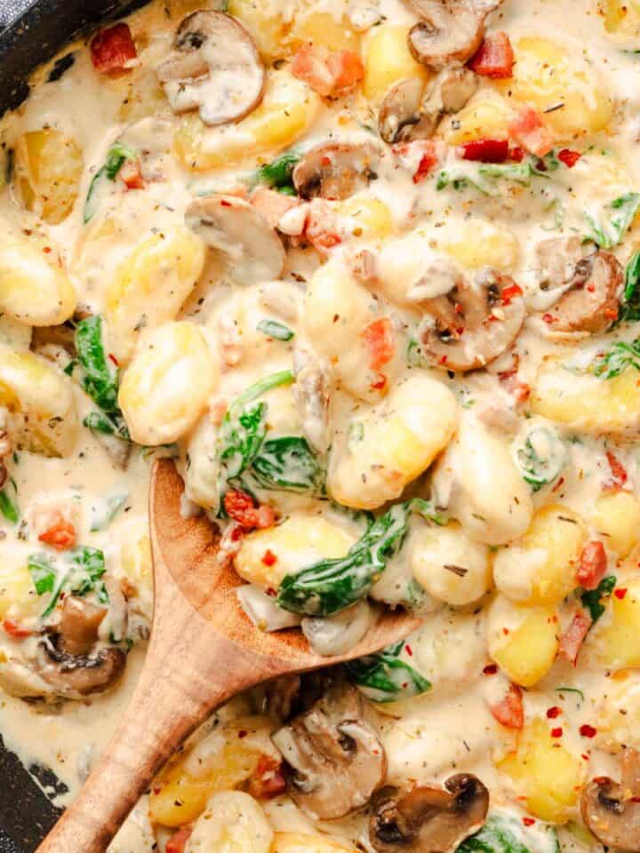 Creamy mushroom spinach gnocchi in a white carbonara sauce.