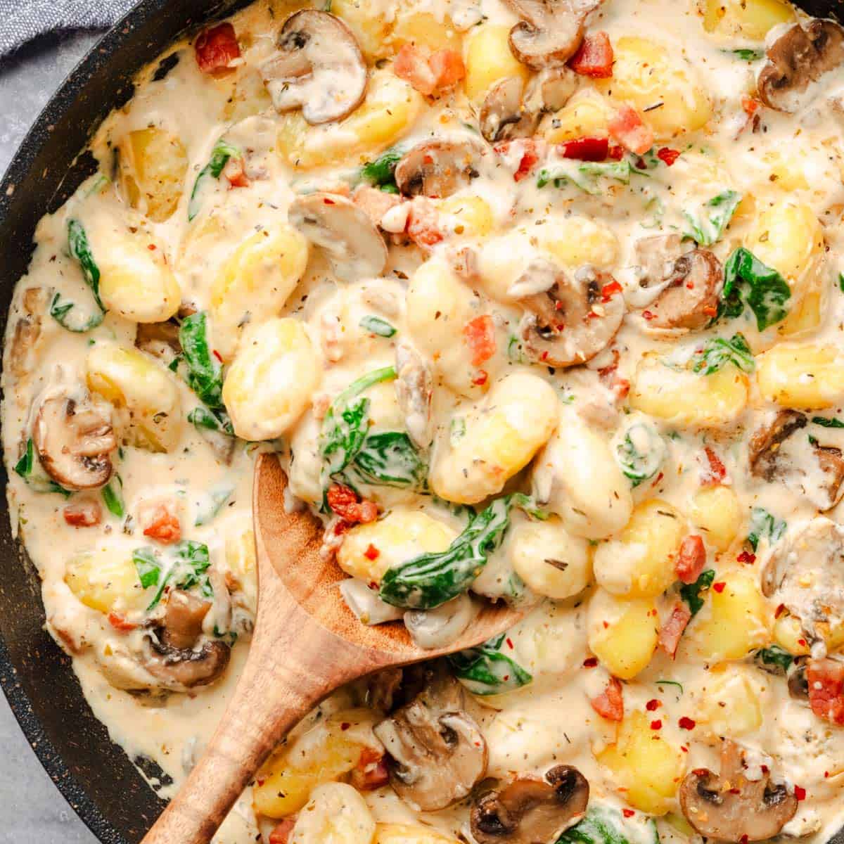 Creamy mushroom spinach gnocchi in a white carbonara sauce.