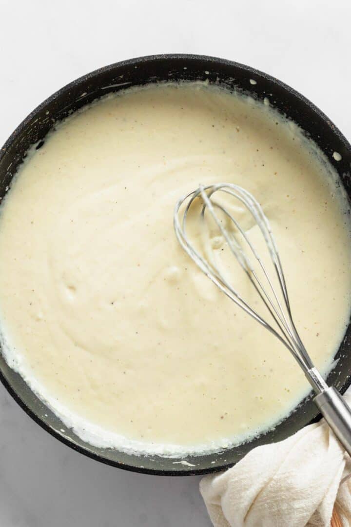 whisking creamy sauce in skillet.