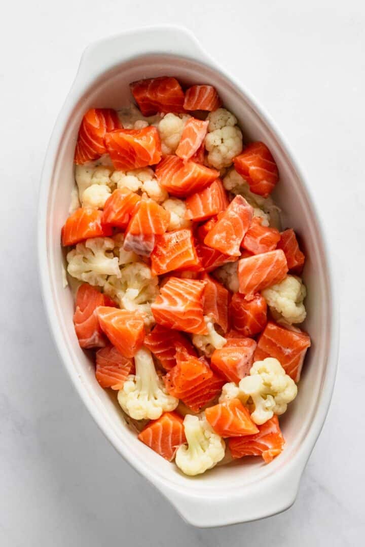 adding chunks of fresh salmon to baking dish.