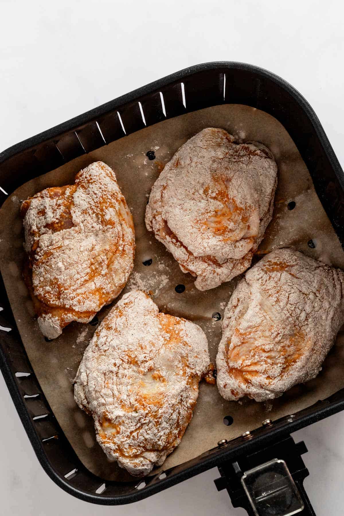 four chicken thighs in air fryer basket before cooking.