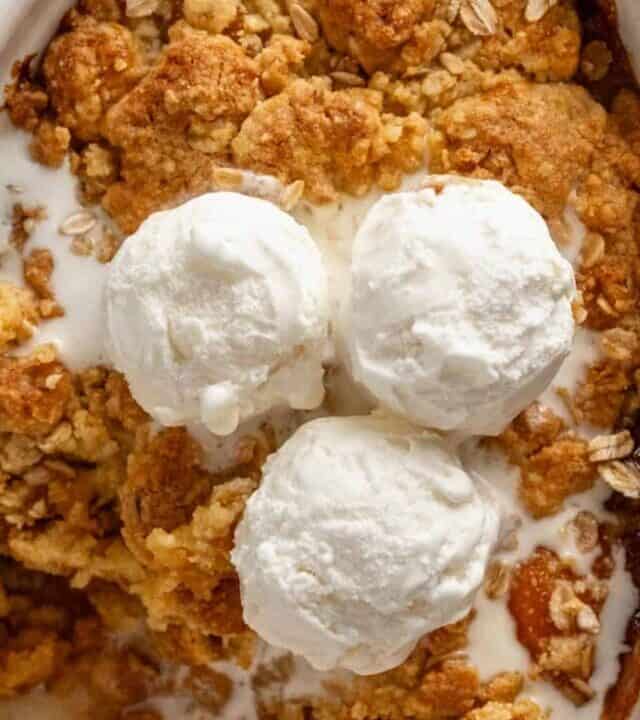 peach cobbler in oval baking dish with ice cream.