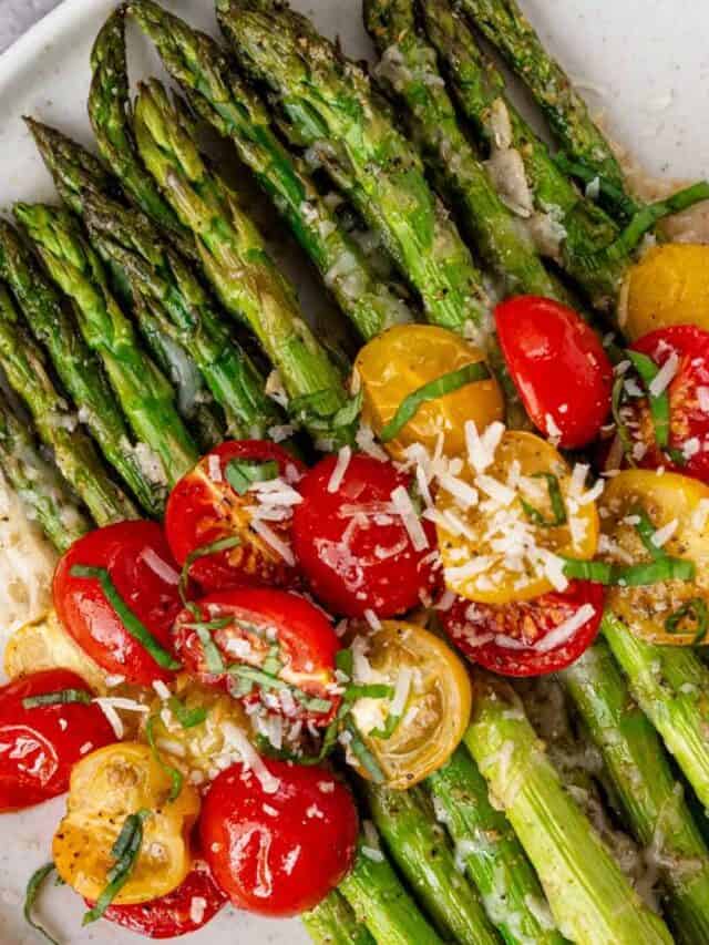 flat lay shot of plated final roasted asparagus with tomatoes, parmesan and basil leaves