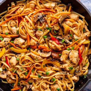 spaghetti noodles with veggies and chicken in skillet.