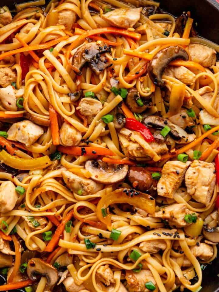 spaghetti noodles with veggies and chicken in skillet.