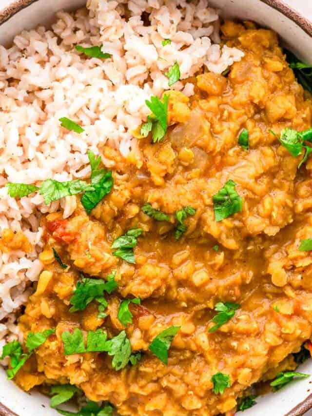 Red Lentil Dhal with cilantro and lime wedges.