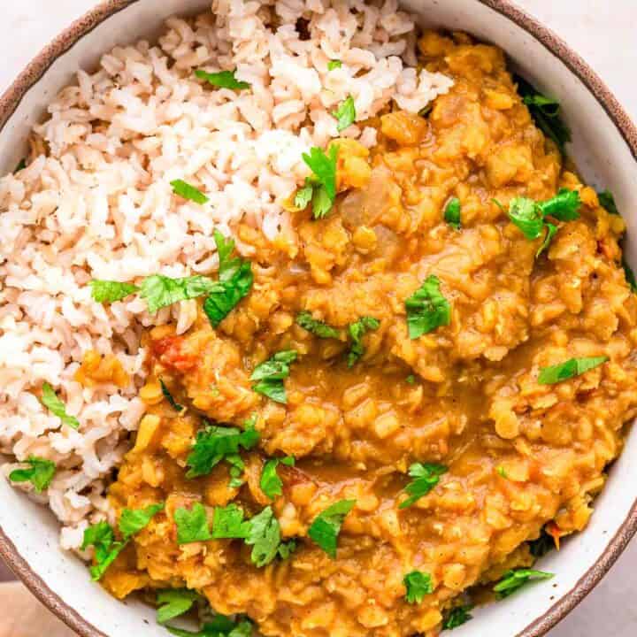 Red Lentil Dhal with cilantro and lime wedges.