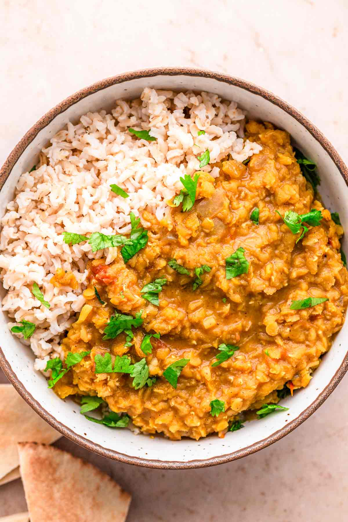 Red Lentil Dhal with cilantro and lime wedges.