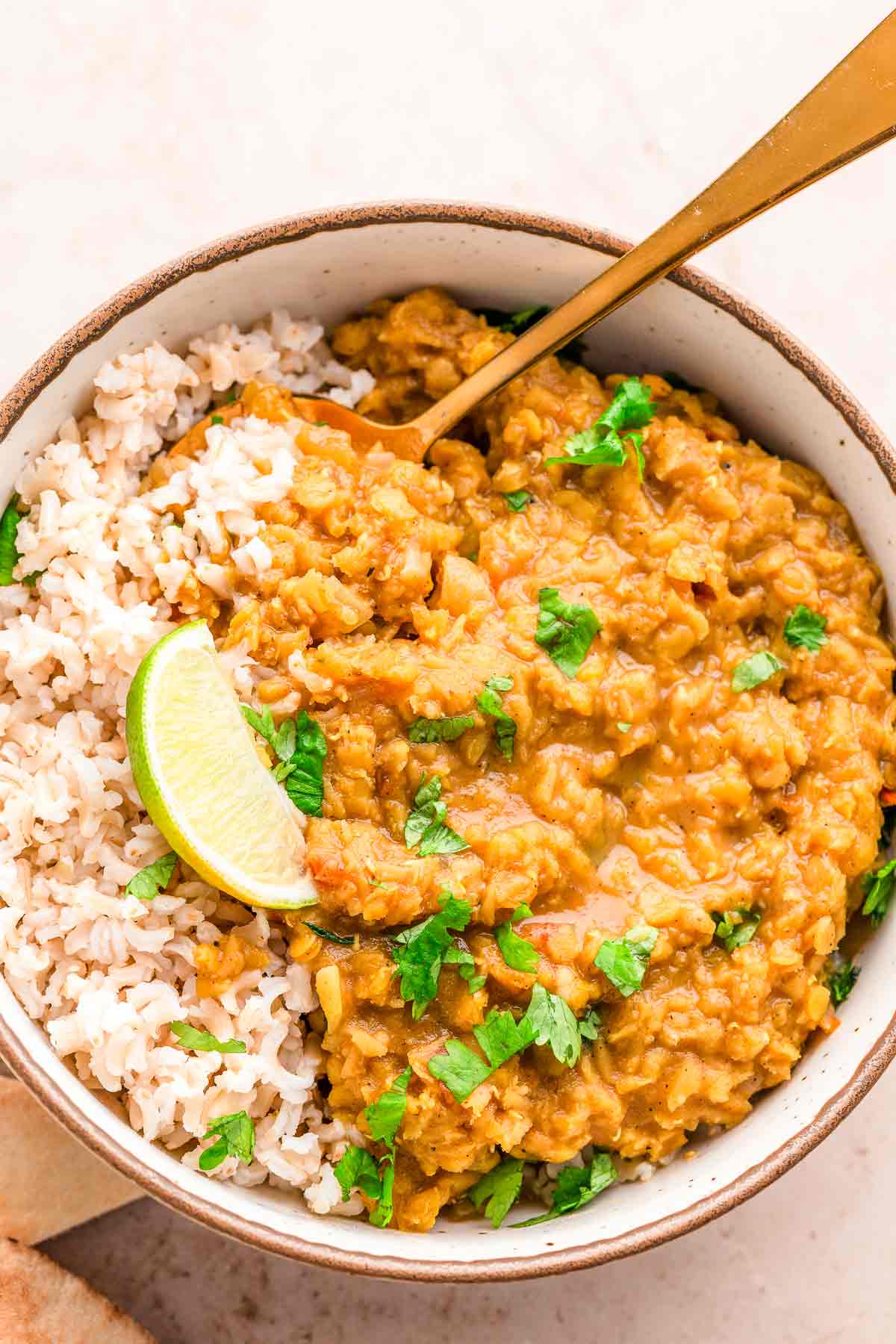 Red Lentil Dhal with cilantro and lime wedges.