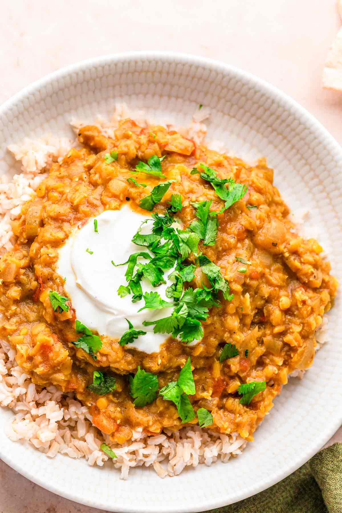 Red Lentil Dhal with cilantro and lime wedges.