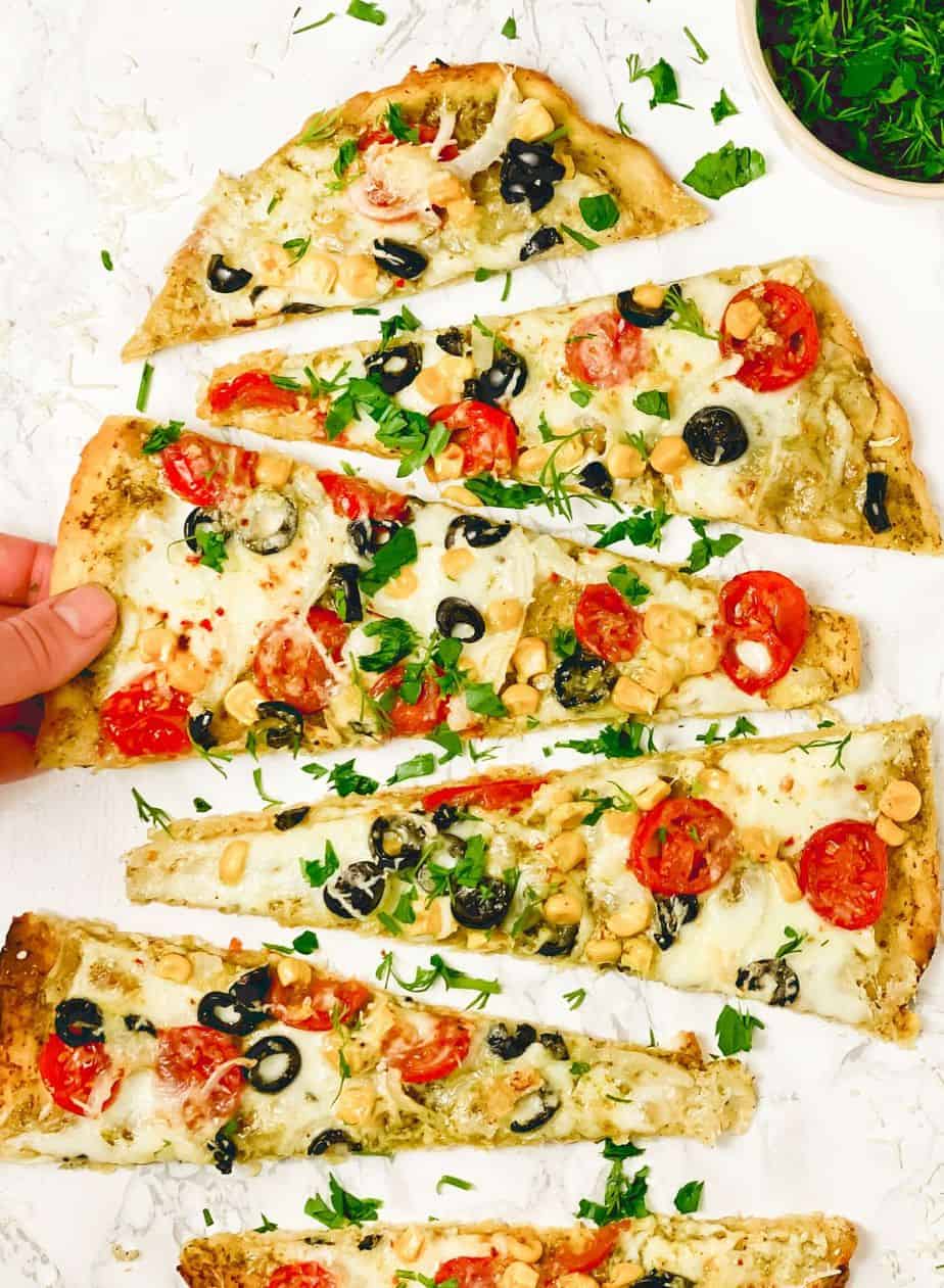 This Easy Basil Pesto Flatbread is very easy to make and has all the best ingredients - cherry tomatoes, onion, corn, olives, garlic oil, spinach leaves, mozzarella. This flavorful flatbread with roasted tomatoes will be the highlight of your dinner and will be gone from the table in seconds - The Yummy Bowl
