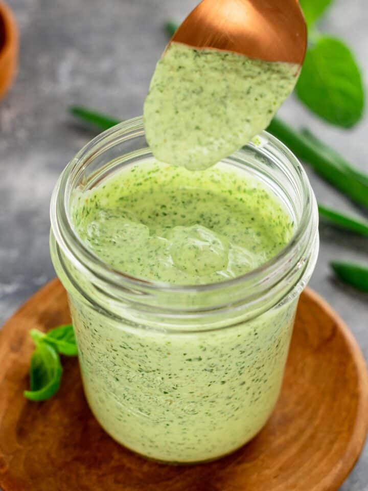 creamy green dip in a jar with spoon drizzle