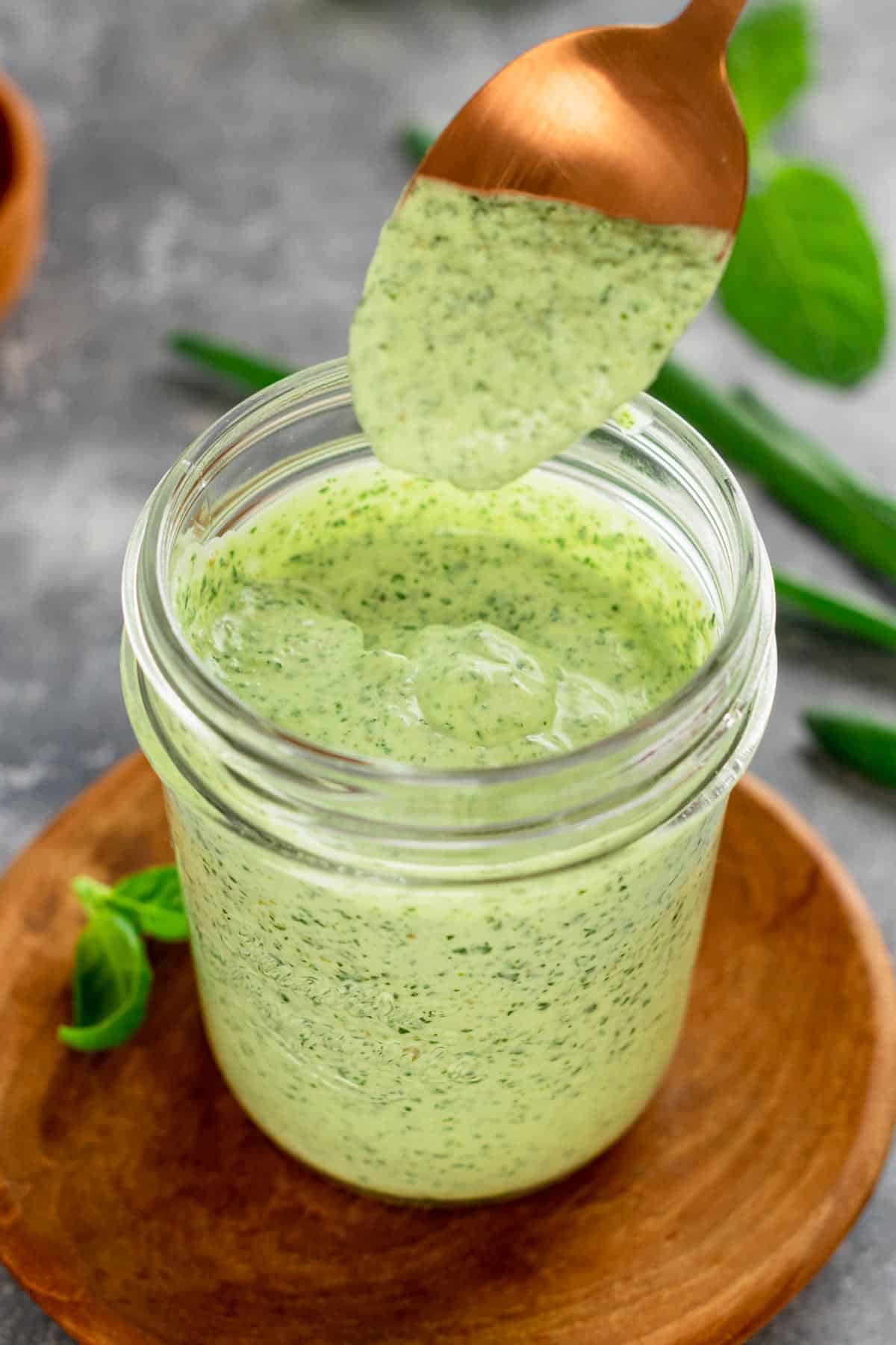 creamy green dip in a jar with spoon drizzle