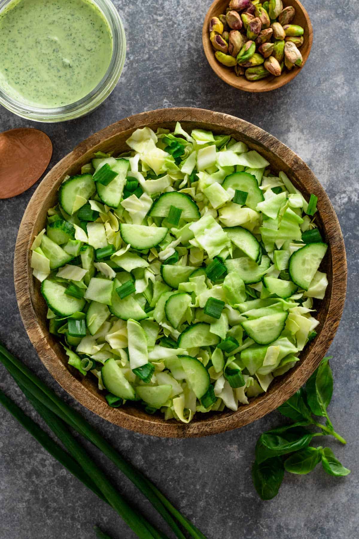 a healthy green salad with cucumbers, pistachios, cabbage and herbs