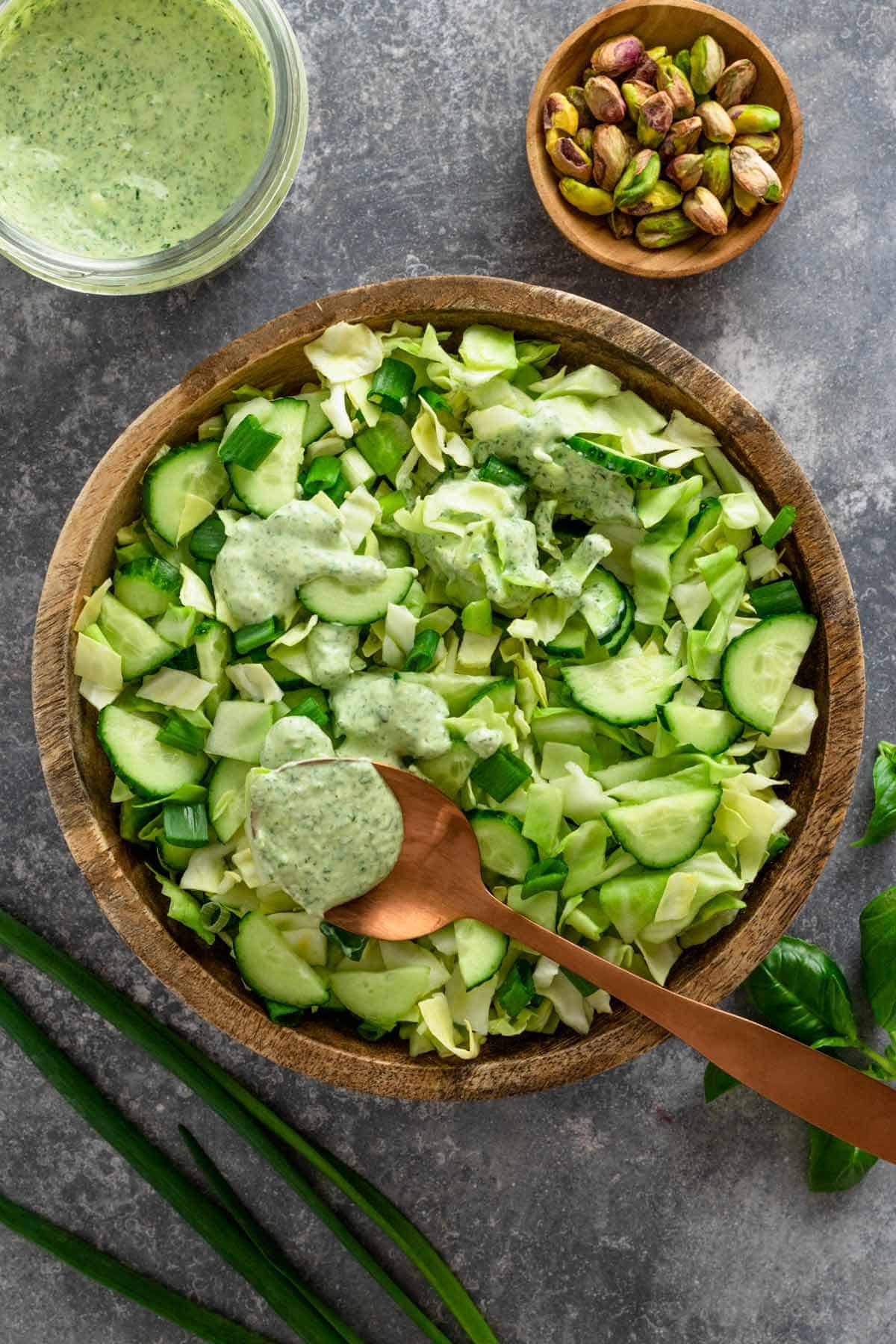 green goddess salad in a bowl with drizzle of green creamy dressing