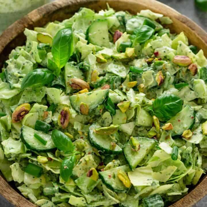 a healthy green salad with cucumbers, pistachios, cabbage and herbs