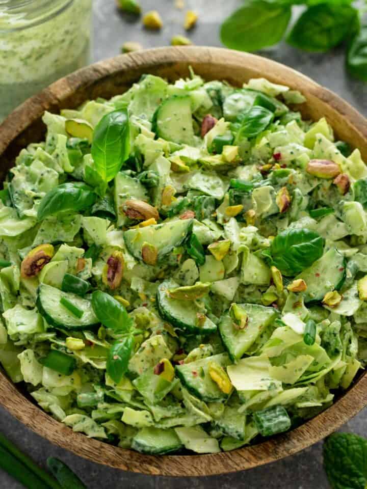 a healthy green salad with cucumbers, pistachios, cabbage and herbs