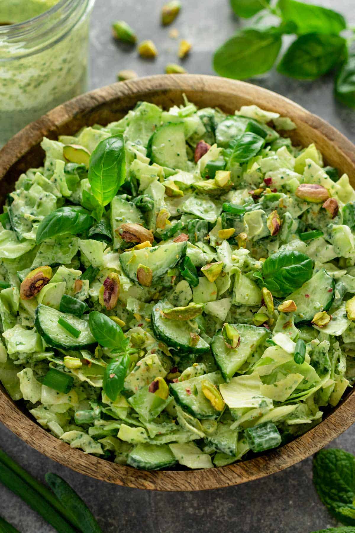 a healthy green salad with cucumbers, pistachios, cabbage and herbs