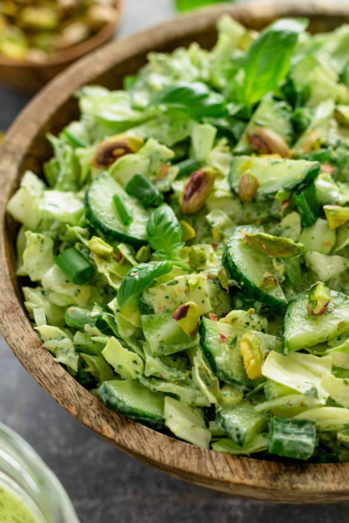 a healthy green salad with cucumbers, pistachios, cabbage and herbs