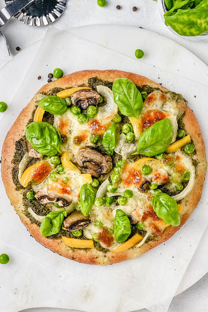 This 10-minute gluten free green pizza is healthy, vegetarian and perfect for Friday pizza night! It is made with my go-to homemade gluten free pizza dough recipe,  topped with green basil pesto, mushrooms, bell pepper, mozzarella and fresh basil leaves. #greenpizza #glutenfreepizza #thickpizzacrust #glutenfreecrust #glutenfreegreenpizza #glutenfreepizzadough