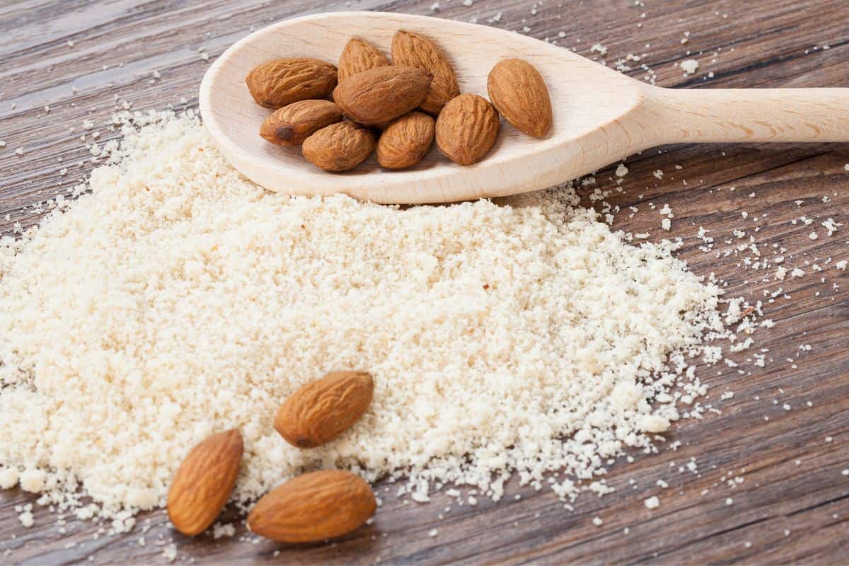 almonds flour and almonds scattered on a wooden table.