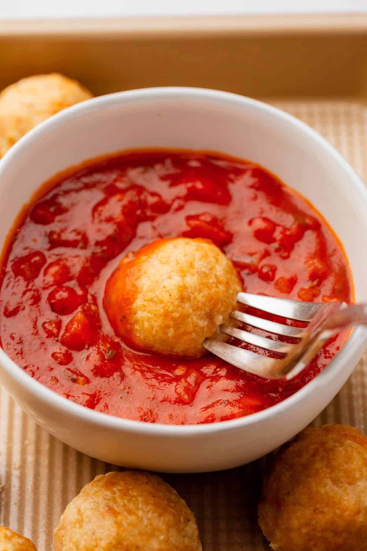 Golden brown ground chicken meatballs with marinara sauce.