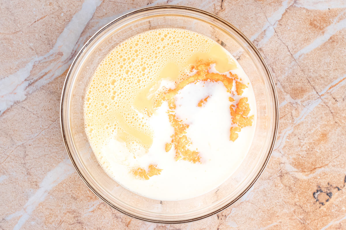 Glass bowl of wet ingredients for pumpkin baked oatmeal: whisked egg, milk, and pumpkin puree before mixing.
