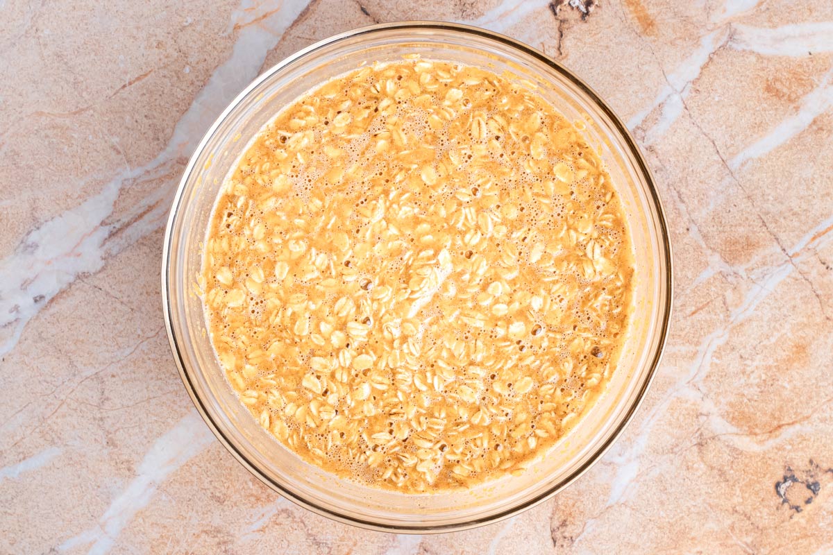 Pumpkin baked oatmeal batter of rolled oats mixed with pumpkin and milk in a glass bowl, ready to pour into the baking dish.