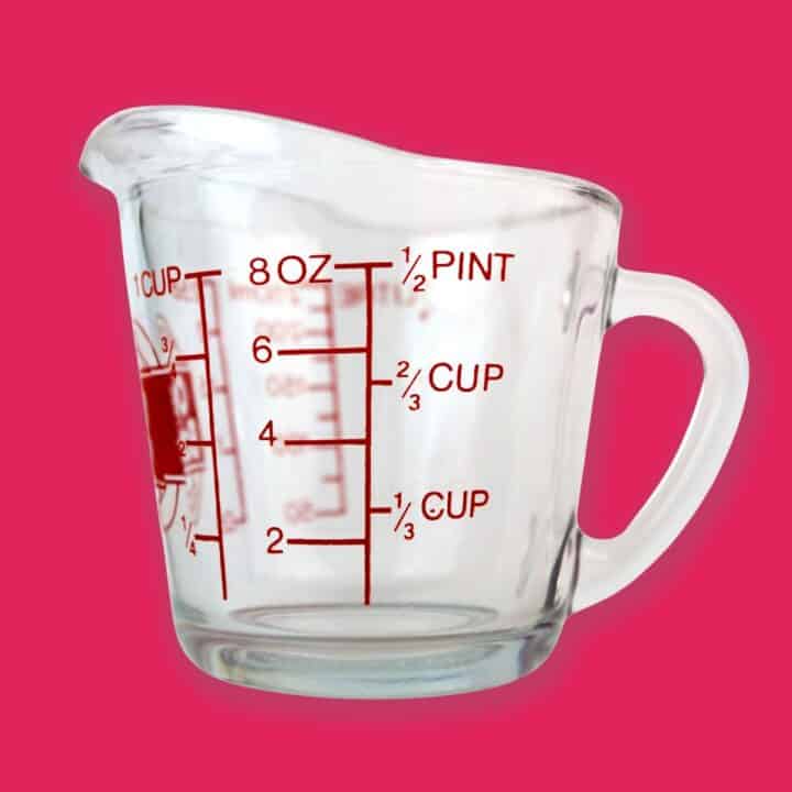 a measuring cup with pink background.
