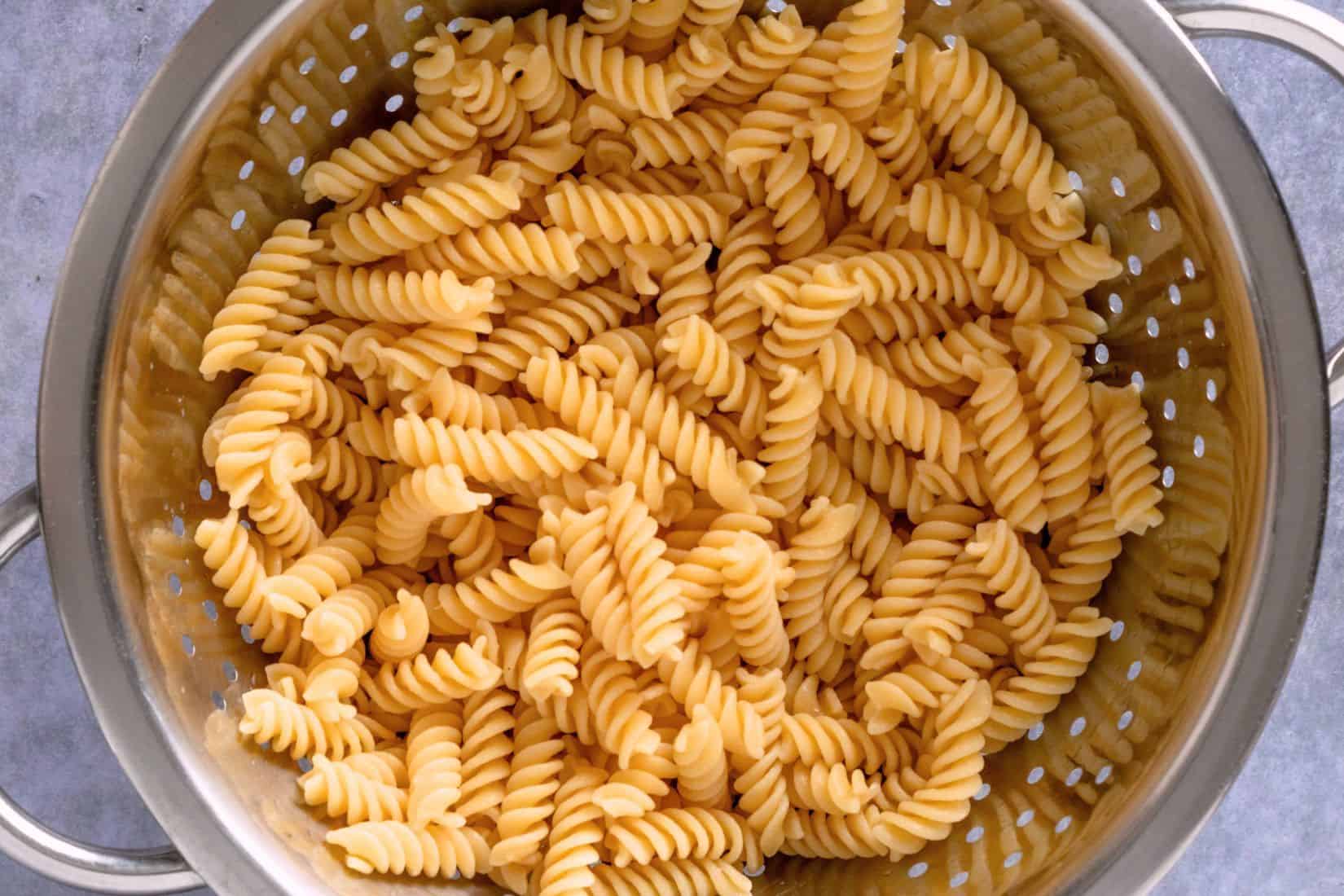 cooked fusilli pasta in a colander.