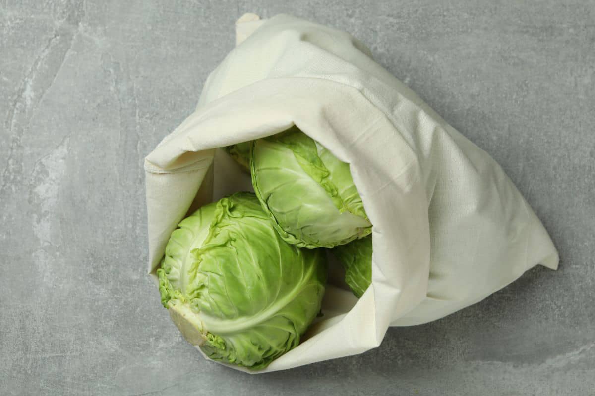green whole cabbage heads in a fabric bag.