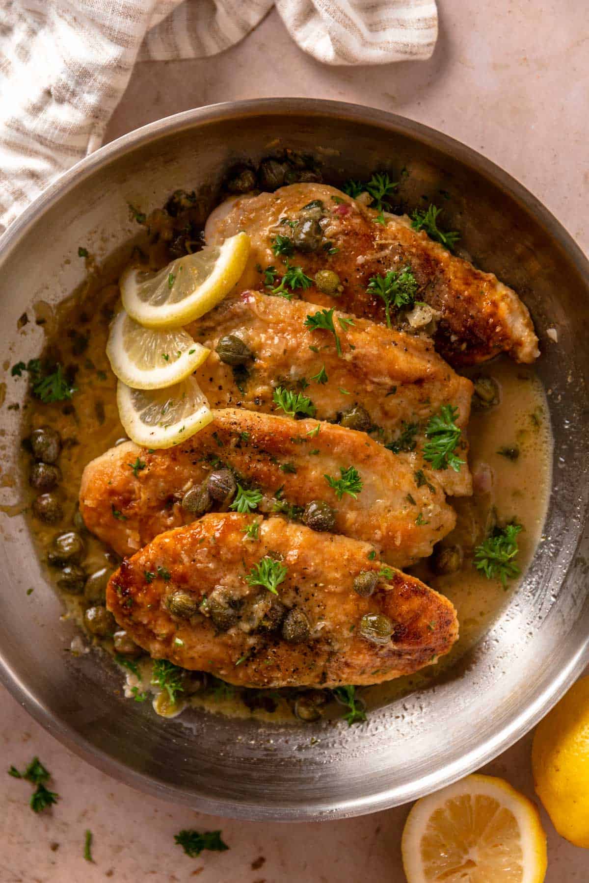 chicken piccata cutlets in skillet with lemon slices, capers and delicious butter sauce