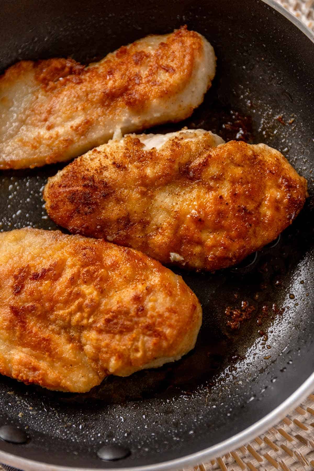 chicken cutlets frying in skillet