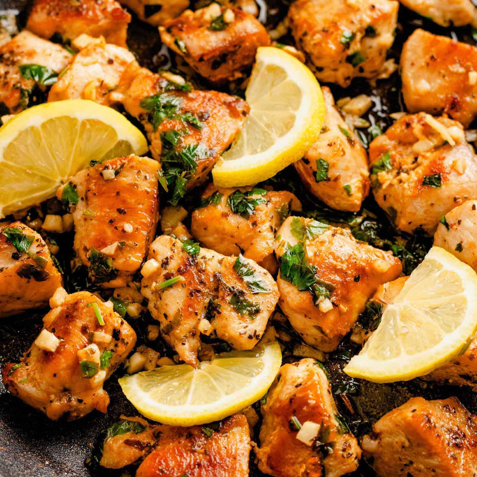 lemon garlic chicken bites in a bowl with lemon slices and label reads: easy skillet lemon garlic chicken bites.