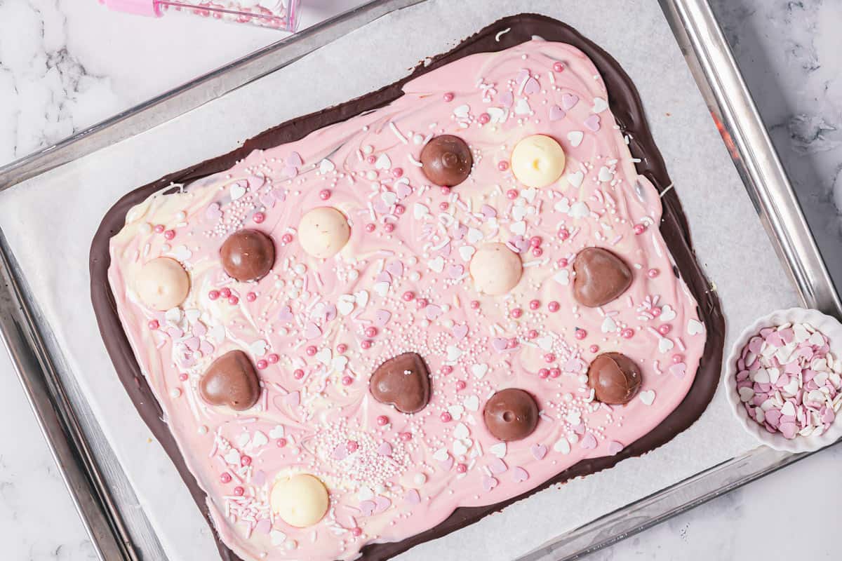 lindor and heart chocolate truffles added to melted pink and white chocolate bark