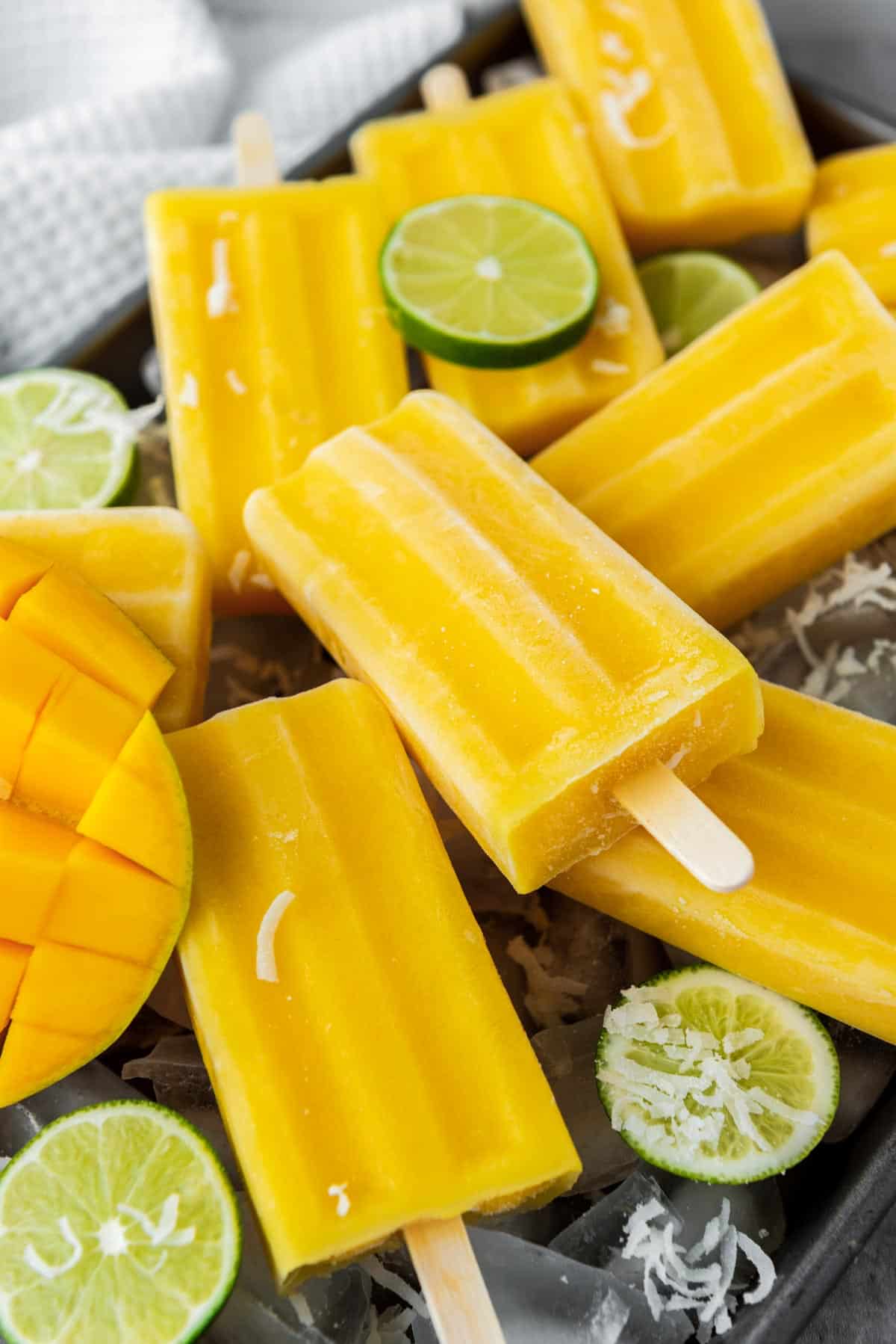 a tray of mango popsicles with lime and shredded coconut