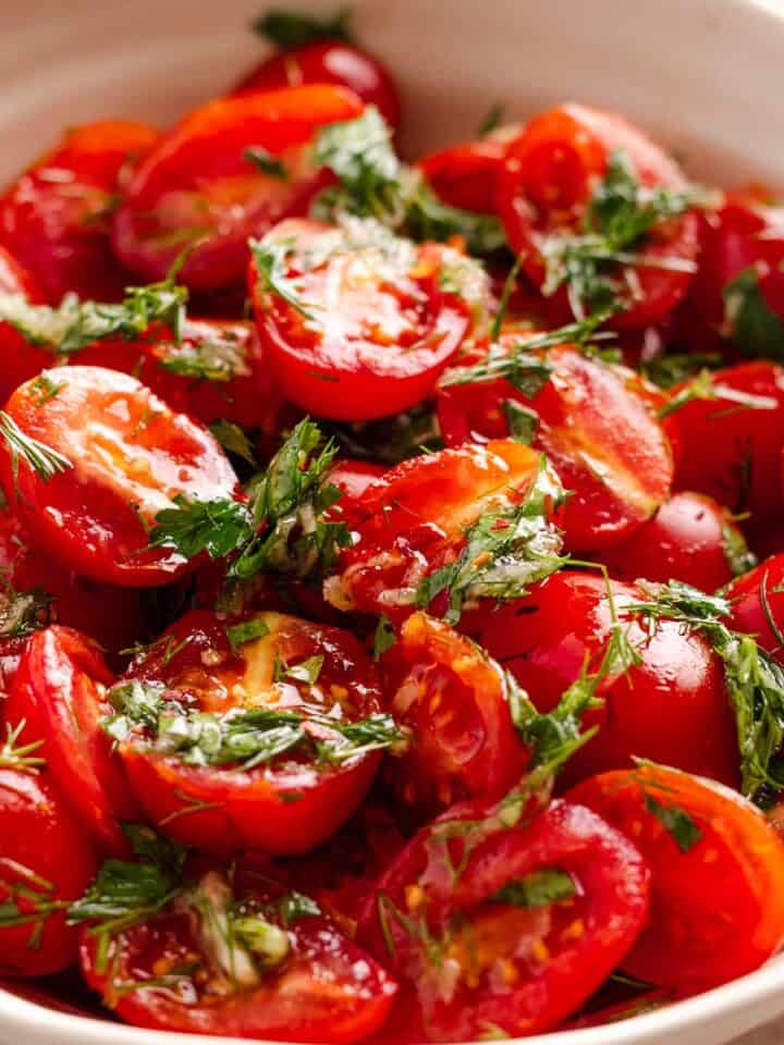 a bowl of marinated cherry tomatoes with herbs and seasonings.