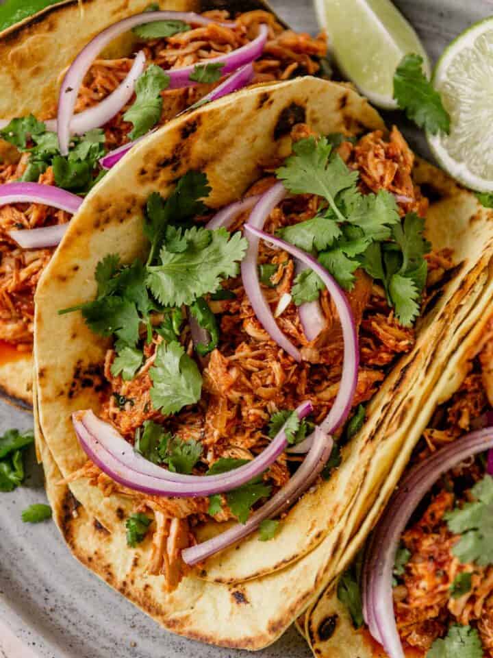 chicken tinga tacos with onion and cilantro on a plate