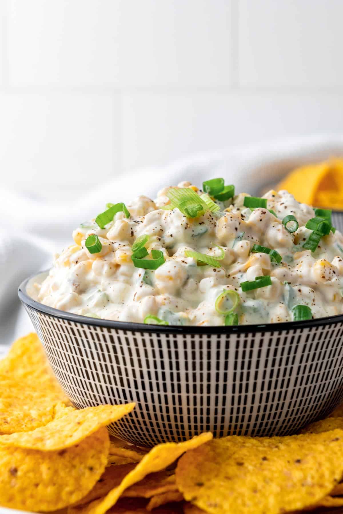 a bowl of mexican corn dip with sour cream and corn chips